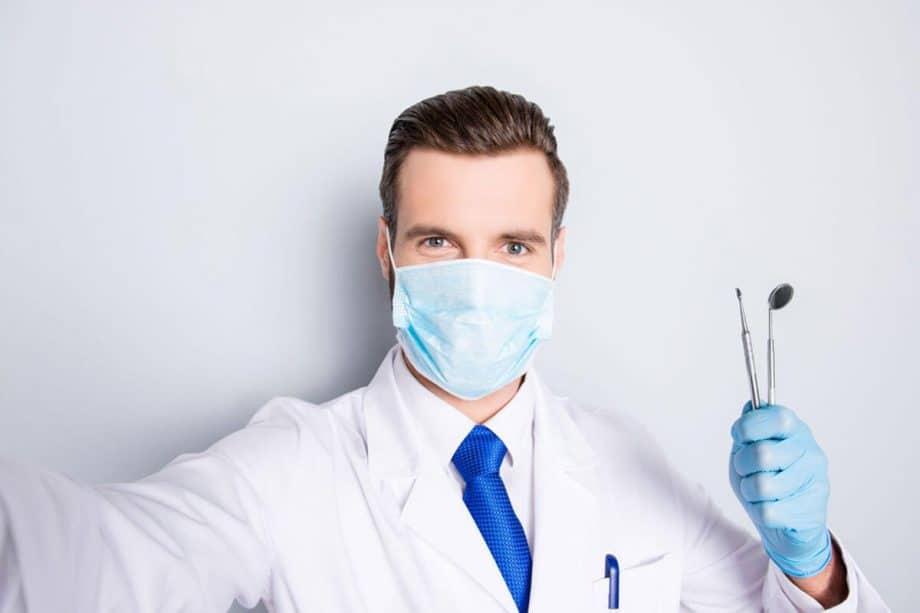 male dentist wearing mask and holding dental tools